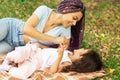 Happy african mother with daughter having fun outside, woman with child playing in the park on the grass Royalty Free Stock Photo