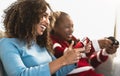 Happy African mother and daughter having fun playing online video games at home Royalty Free Stock Photo