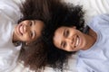 Happy african mother and daughter lying on bed, top view Royalty Free Stock Photo