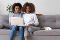 Happy african mother and teen daughter using laptop on sofa Royalty Free Stock Photo