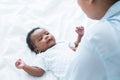 Happy African Nigerian newborn baby lying on white bed at home with mother talking and playing. Innocence infant with curly hair Royalty Free Stock Photo