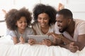 Happy african parents with daughter using tablet lying on bed Royalty Free Stock Photo