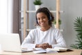 Happy african schoolgirl wearing headphones e-learning using computer Royalty Free Stock Photo