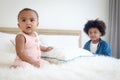 Happy African siblings in family, portrait of cute toddle baby infant sister girl sitting on white bed with her brother boy with Royalty Free Stock Photo
