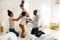 Happy african spouses with children jumping and playing on bed Royalty Free Stock Photo