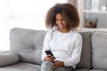 Happy african teen girl holding smartphone using apps at home Royalty Free Stock Photo