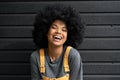 Happy African teen hipster girl with Afro hair laughing at camera, headshot.