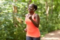Happy african woman in earphones running in park Royalty Free Stock Photo