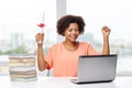 Happy african woman with laptop, books and diploma