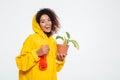 Happy african woman in raincoat holding plant Royalty Free Stock Photo