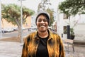 Happy African woman smiling in front of a camera in city