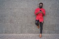 Happy african young man listening music with headphones outdoors while wearing safety mask - Focus on face Royalty Free Stock Photo