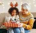 Happy afro american curly boy sitting on grandmother lap with christmas present, smiling at camera Royalty Free Stock Photo