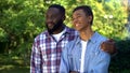 Happy afro-american dad hugging teenage son standing outdoors together, love Royalty Free Stock Photo