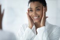 Happy Afro American girl in bathrobe examining smooth facial skin Royalty Free Stock Photo
