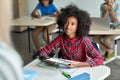 Happy Afro American schoolgirl looking at teacher holding tablet in classroom. Royalty Free Stock Photo