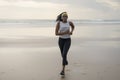Happy afro American woman running on the beach - young attractive and athletic black girl training outdoors doing jogging workout Royalty Free Stock Photo