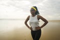 Happy afro American woman running on the beach - young attractive and athletic black girl training outdoors tired after jogging Royalty Free Stock Photo