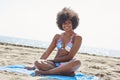 Happy afro american woman sitting on beach looking away Royalty Free Stock Photo