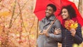 Happy afro couple walking under umbrella at rainy autumn day Royalty Free Stock Photo