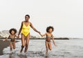 Happy Afro family having fun running on the beach during summer time