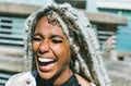 Happy afro girl with blond dreadlocks laughing outdoor with urban city context as background - Millennial black woman having fun Royalty Free Stock Photo