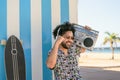 Happy Afro man having fun listening to music with wireless headphones and vintage boombox on the beach during summer Royalty Free Stock Photo