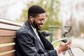 Happy afro man sitting in park and listening music Royalty Free Stock Photo