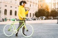 Happy Afro man using mobile smartphone outdoor - Young guy having fun listening music with headphones while riding with bike Royalty Free Stock Photo