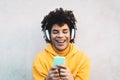 Happy Afro man using mobile smartphone outdoor - Young guy having fun listening music with wireless headphones outdoor Royalty Free Stock Photo