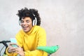 Happy Afro man using mobile smartphone outdoor - Young guy having fun listening music with wireless headphones Royalty Free Stock Photo