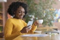 Happy afro woman drinking coffee and using mobile phone