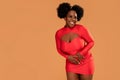 Happy afro Woman posing in fashionable red mini dress, looking at the camera and smiling. Glamour makeup. Date time Royalty Free Stock Photo