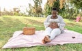 Happy Afro woman touching her pregnant belly doing heart shape with hands in public park Royalty Free Stock Photo
