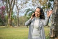 Happy aged Asian woman making a hello gesture, bumped into her neighbor in the park