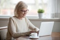 Happy aged woman busy using laptop at home Royalty Free Stock Photo