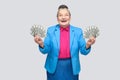 Happy aged woman holding many american dollars