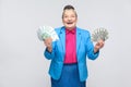 Happy aged woman holding many euro and dollars