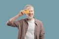 Happy albino man holding credit card in front of his eye on turquoise studio background