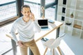 Happy ambitious man sitting on the corner of the table