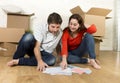 happy American couple sitting on floor moving in new house looking blueprints Royalty Free Stock Photo