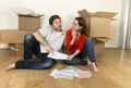 happy American couple sitting on floor moving in new house looking blueprints
