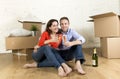 Happy American couple sitting on floor unpacking together celebrating with champagne toast moving in a new house Royalty Free Stock Photo