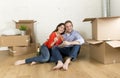 Happy American couple sitting on floor unpacking together celebrating with champagne toast moving in a new house Royalty Free Stock Photo