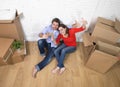 Happy American couple sitting on floor unpacking together celebrating moving to new house flat or apartment Royalty Free Stock Photo