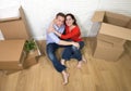 Happy American couple sitting on floor unpacking together celebrating moving to new house flat or apartment Royalty Free Stock Photo