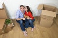 Happy American couple sitting on floor unpacking together celebrating moving to new house flat or apartment Royalty Free Stock Photo
