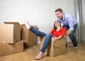 Happy American couple unpacking moving in new house playing with unpacked cardboard boxes Royalty Free Stock Photo