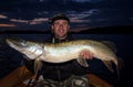 Happy angler with monster pike at evening time Royalty Free Stock Photo