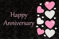 Happy Anniversary greeting with white and pink hearts with candy hearts on black